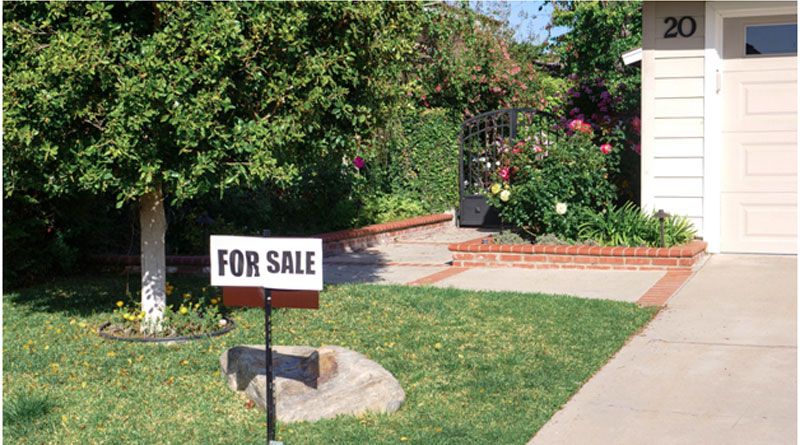 A house’s front yard with a “For Sale” sign